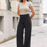 Woman wearing Black Brown Plaid high-waisted wide-leg pants with a neutral short-sleeve top outdoors