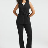 Woman wearing black tailored ponte vest with self-tie belt and matching black dress pants, full front view