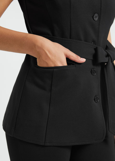 Close-up of black ponte vest showing functional front pocket, button closure and self-tie waist belt