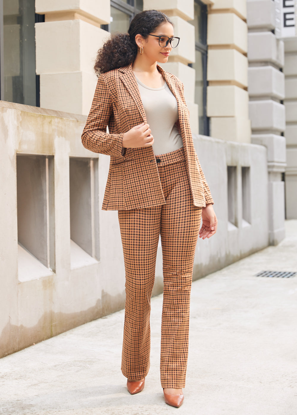 Woman wearing matching Camel Mini Houndstooth blazer and pants with a neutral top and brown heels outdoors