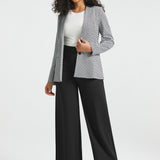 Full-length front view of woman wearing the Black Ivory Catstooth Classic Blazer open with a white top and black wide-leg pants