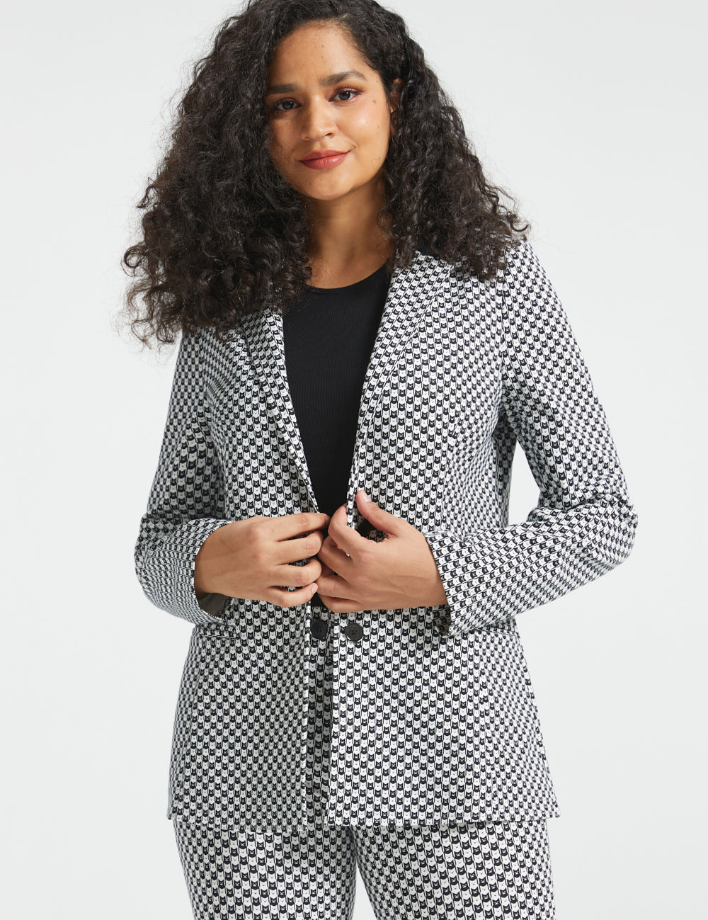 Woman wearing the Betabrand Black Ivory Catstooth Classic Blazer with matching cat print pants and a black top, front view