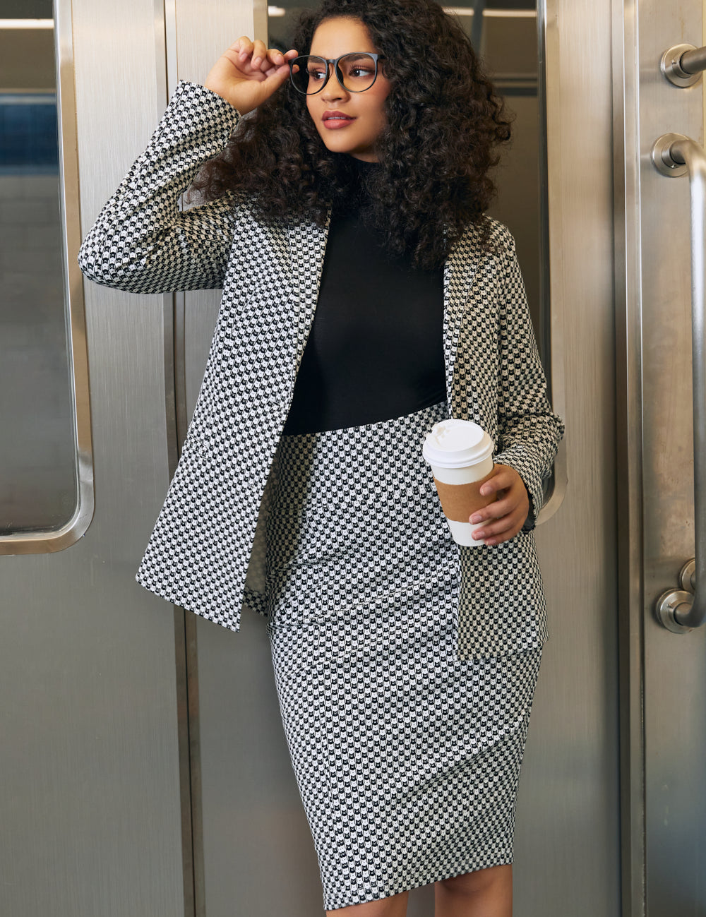 Woman wearing the Black Ivory Catstooth high-waist pencil skirt with matching blazer and black turtleneck in an office setting
